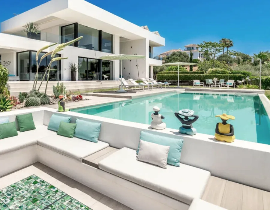 Piscine d'une villa bordée d'un massif de succulentes et de haies taillées.